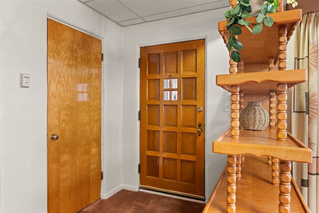 foyer with a paneled ceiling and dark carpet