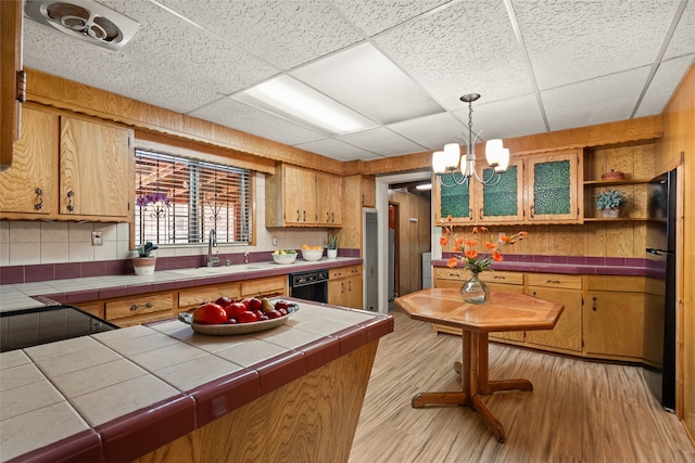 kitchen with an inviting chandelier, tile countertops, light hardwood / wood-style flooring, black appliances, and sink