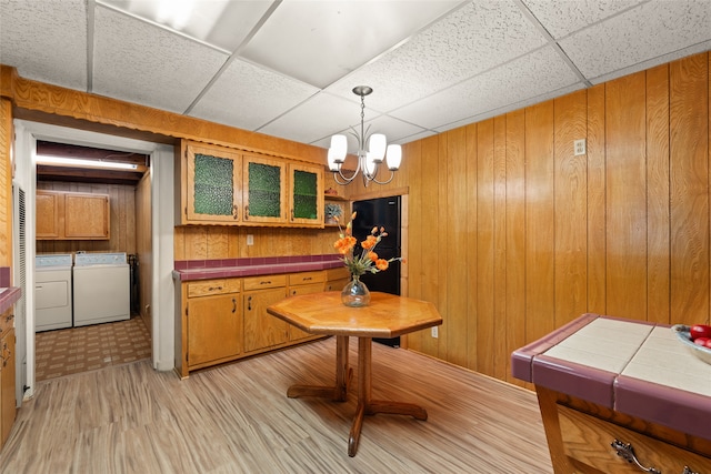 interior space featuring a paneled ceiling, wood walls, a chandelier, and separate washer and dryer