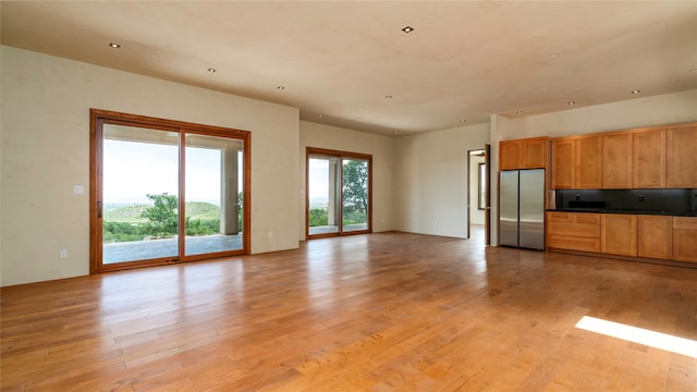 kitchen featuring tasteful backsplash, stainless steel refrigerator, and light wood-type flooring