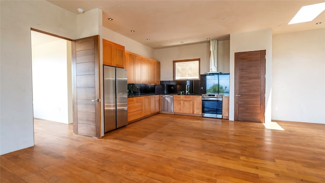 kitchen with light hardwood / wood-style flooring, appliances with stainless steel finishes, and wall chimney range hood