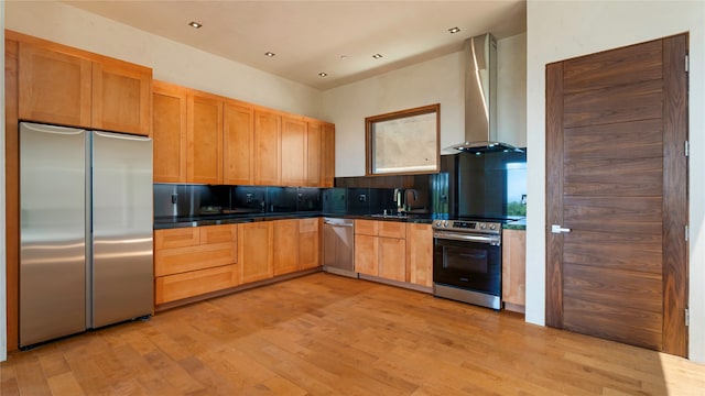 kitchen featuring light hardwood / wood-style floors, wall chimney range hood, appliances with stainless steel finishes, and tasteful backsplash