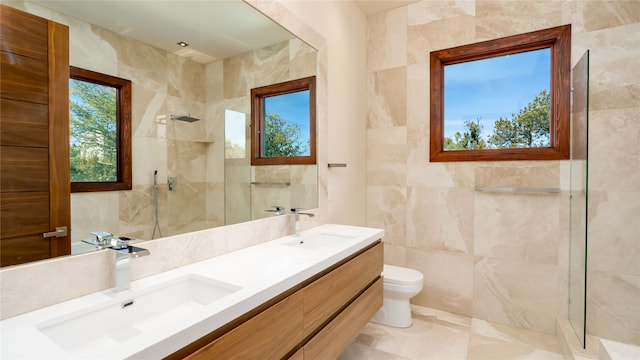 bathroom featuring tile walls, dual bowl vanity, an enclosed shower, and toilet