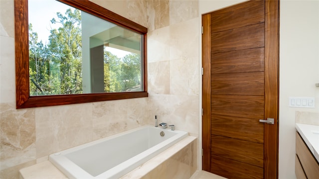 bathroom featuring vanity, tiled tub, and tile walls