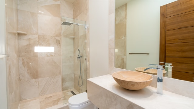 bathroom featuring toilet, a tile shower, and vanity