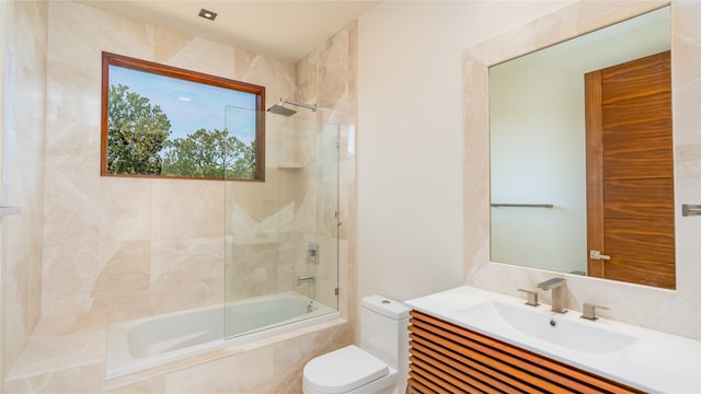 full bathroom featuring tile walls, combined bath / shower with glass door, toilet, and vanity