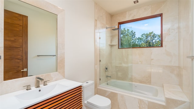 full bathroom featuring tile walls, toilet, tiled shower / bath combo, and vanity