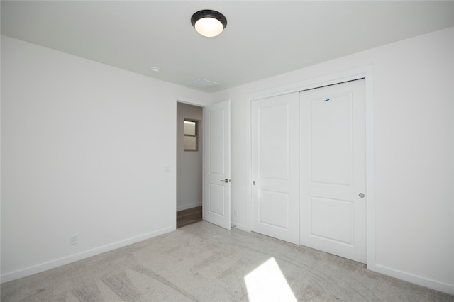 unfurnished bedroom featuring a closet and light colored carpet