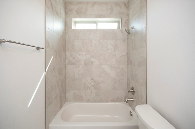 bathroom featuring tiled shower / bath combo and toilet