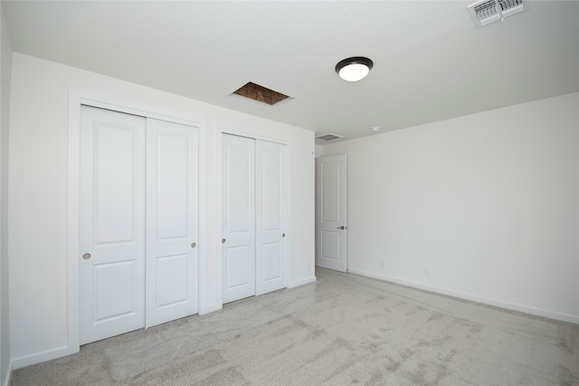 unfurnished bedroom with light colored carpet and two closets