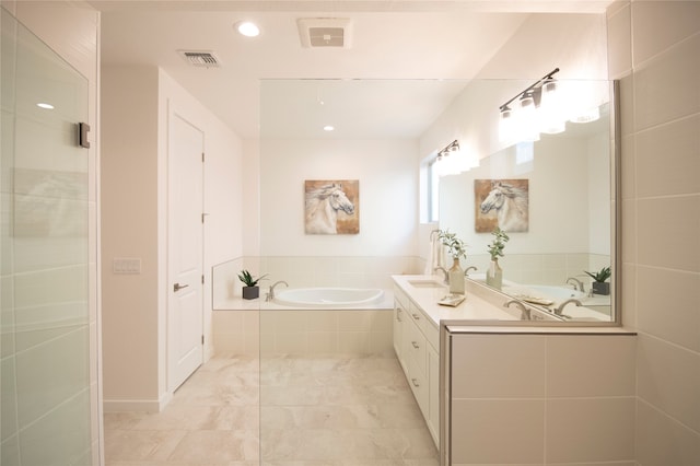 bathroom featuring tiled tub, vanity, and tile flooring