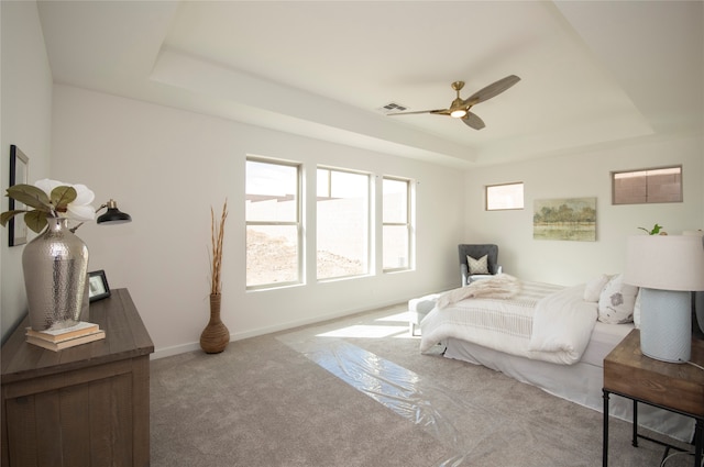 bedroom featuring ceiling fan, a tray ceiling, and carpet