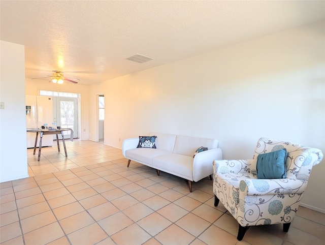 living room featuring ceiling fan, a textured ceiling, and light tile patterned floors