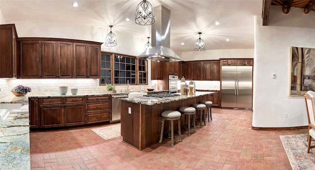 kitchen with tasteful backsplash, stainless steel appliances, pendant lighting, a kitchen island with sink, and island exhaust hood