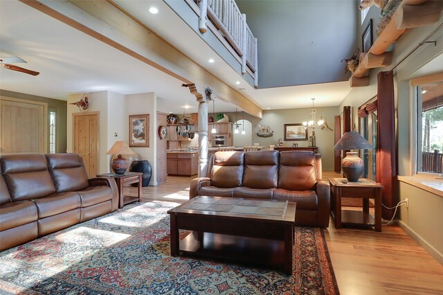 living room featuring light hardwood / wood-style flooring, a wood stove, ceiling fan, and vaulted ceiling with beams