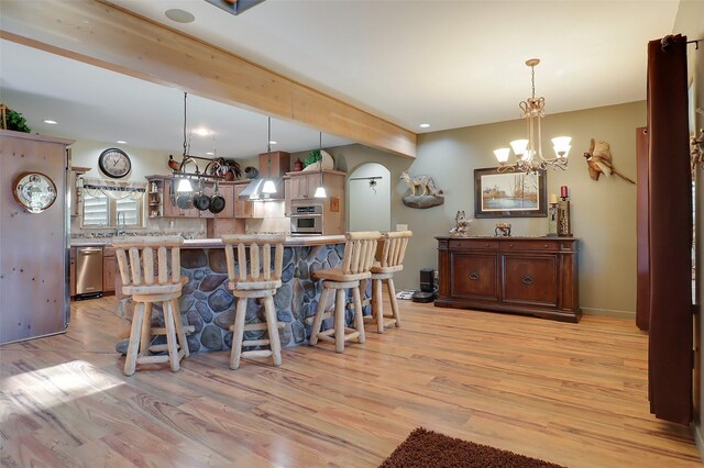 kitchen featuring backsplash, hanging light fixtures, a breakfast bar, and light wood-type flooring