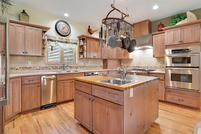 kitchen with a center island with sink, stainless steel appliances, a notable chandelier, light wood-type flooring, and sink