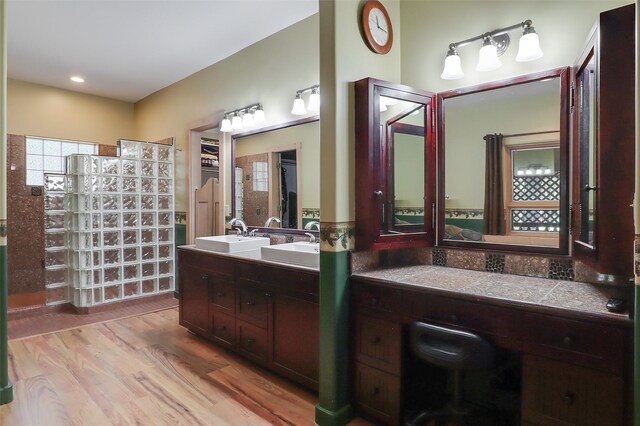 bathroom with vanity, plenty of natural light, a bath to relax in, and hardwood / wood-style flooring