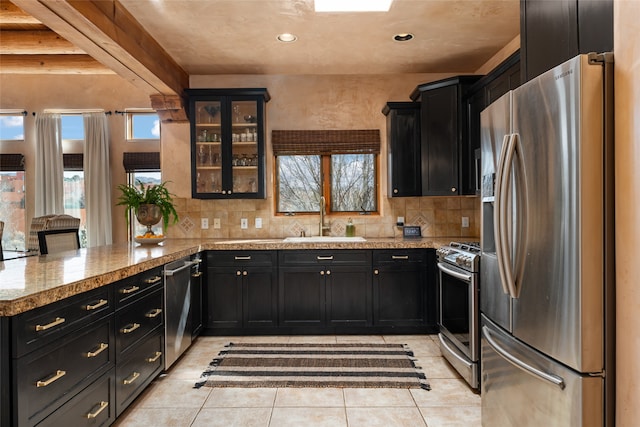 kitchen with sink, light tile patterned floors, kitchen peninsula, stainless steel appliances, and beam ceiling