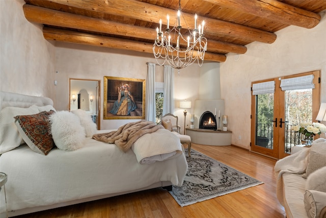 bedroom with wood ceiling, an inviting chandelier, hardwood / wood-style flooring, beamed ceiling, and access to exterior