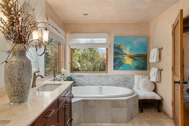 bathroom with tiled tub, vanity, and tile patterned floors