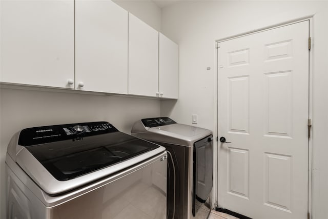 laundry room featuring light tile patterned floors, washing machine and dryer, and cabinets