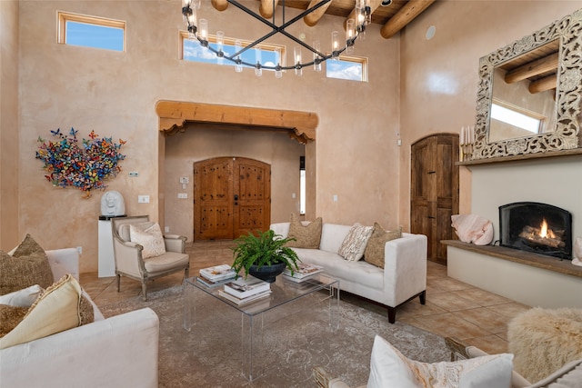 living room featuring light tile patterned floors, a towering ceiling, a chandelier, and beamed ceiling