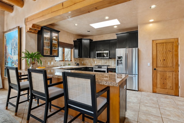 kitchen featuring a kitchen bar, light tile patterned floors, light stone countertops, and appliances with stainless steel finishes