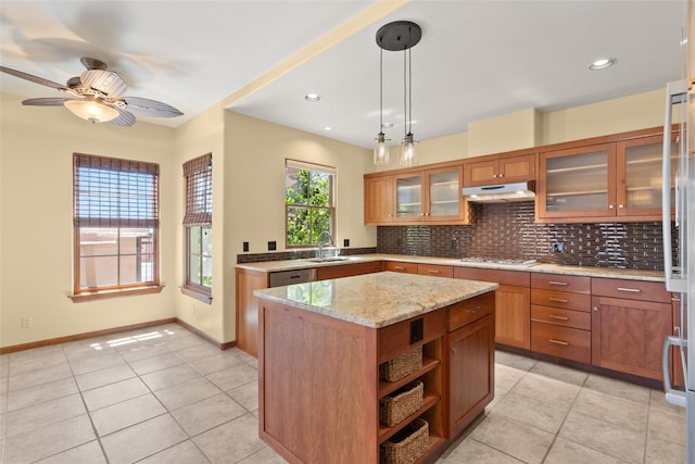 kitchen with ceiling fan, stainless steel gas cooktop, a kitchen island, decorative light fixtures, and light stone countertops