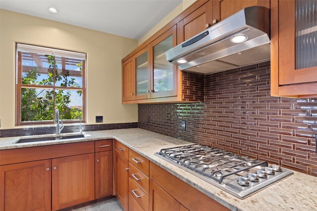 kitchen with stainless steel gas stovetop, light stone counters, and tasteful backsplash