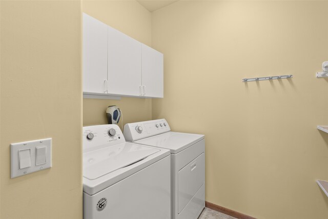 clothes washing area featuring washer and dryer and cabinets