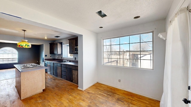 kitchen featuring sink, dark brown cabinetry, a center island, and light wood-type flooring