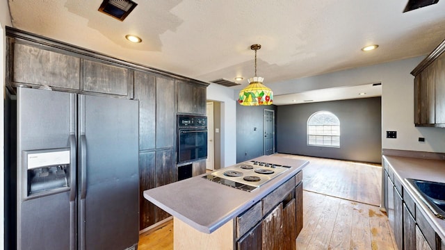 kitchen with light hardwood / wood-style floors, dark brown cabinets, stainless steel fridge, and white electric stovetop