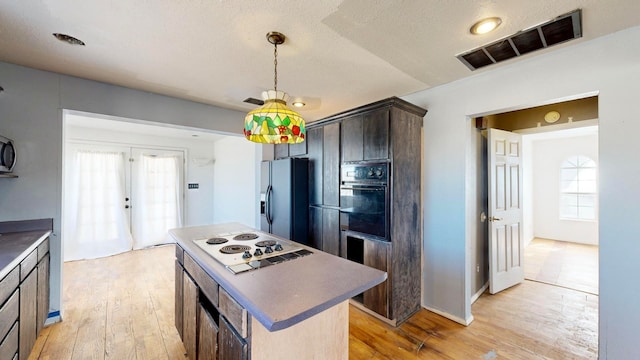 kitchen featuring oven, light wood-type flooring, a kitchen island, and refrigerator with ice dispenser