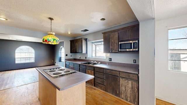 kitchen featuring sink, light hardwood / wood-style flooring, a textured ceiling, dark brown cabinetry, and a center island