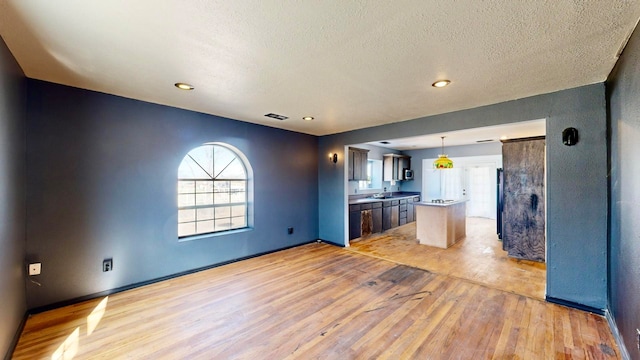 kitchen featuring a kitchen island, a textured ceiling, light hardwood / wood-style floors, and hanging light fixtures