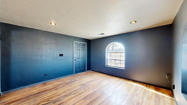 unfurnished room featuring light hardwood / wood-style floors and a textured ceiling