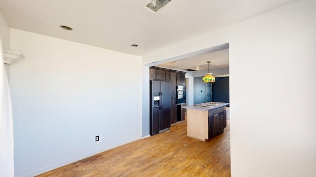 kitchen with dark brown cabinetry, a kitchen island, refrigerator with ice dispenser, oven, and light hardwood / wood-style floors