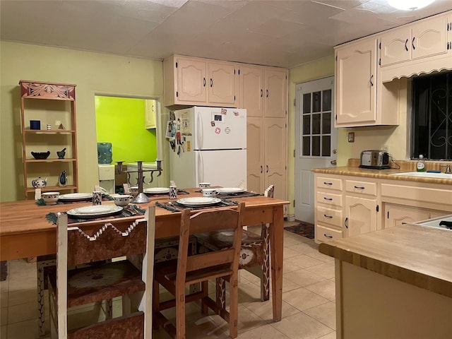 kitchen featuring light tile patterned floors, white refrigerator, white cabinetry, and sink