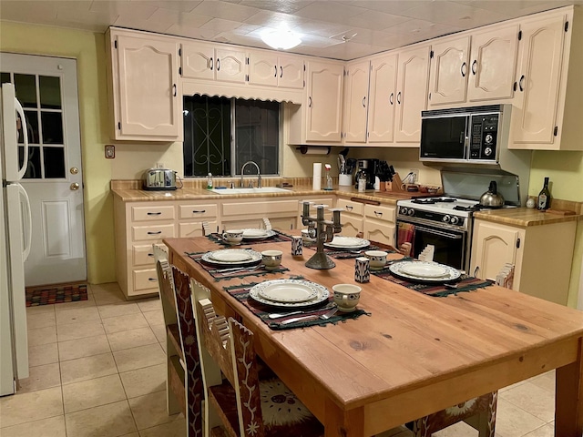 kitchen with white appliances, sink, and light tile patterned floors