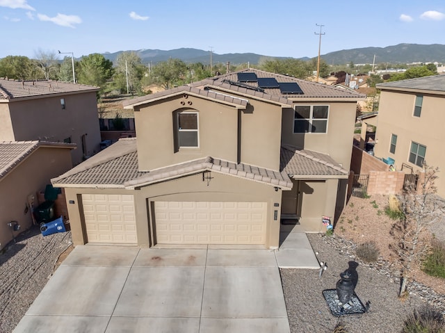 view of front of house with a mountain view, a garage, and solar panels