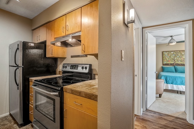 kitchen featuring ceiling fan, stainless steel range with electric stovetop, a textured ceiling, and wood-type flooring