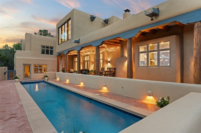 pool at dusk with a patio