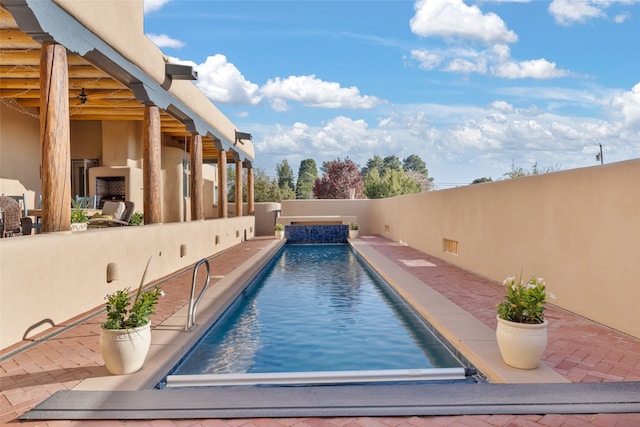 view of pool featuring pool water feature, an outdoor fireplace, and a patio area