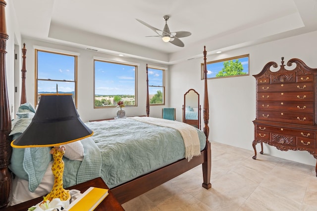 bedroom with light tile patterned floors, a raised ceiling, and a ceiling fan