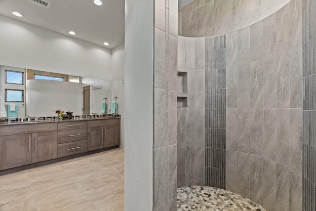 full bathroom with double vanity, recessed lighting, a tile shower, and a sink