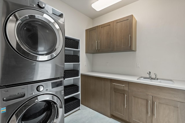 clothes washing area featuring a sink, cabinet space, and stacked washer / dryer