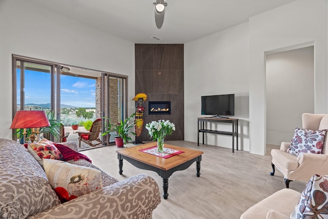 living room with ceiling fan and a tile fireplace