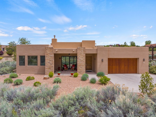 adobe home with a garage, driveway, and stucco siding