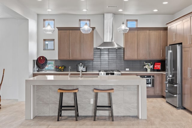 kitchen featuring a breakfast bar, wall chimney range hood, backsplash, appliances with stainless steel finishes, and light countertops